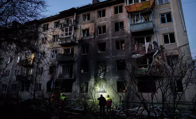 Municipal workers look at a residential building damaged after a Russian attack on Kyiv, Ukraine, on Friday, Nov. 14, 2025. (AP Photo/Evgeniy Maloletka)