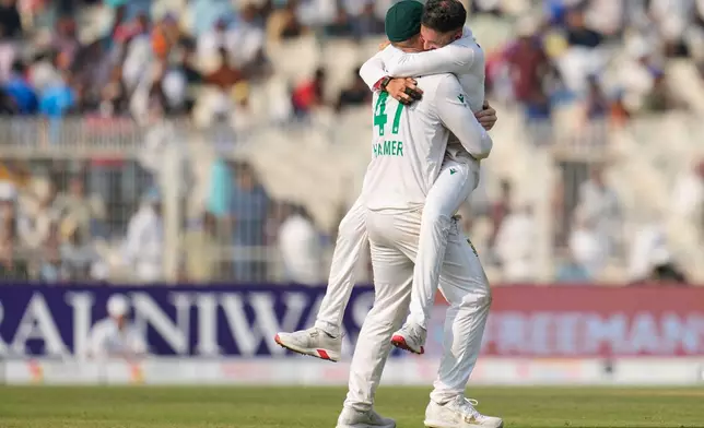 South Africa's Simon Harmer, left, and teammate Keshav Maharaj celebrate after their win on the third day of the first cricket test match against India in Kolkata, India, Sunday, Nov. 16, 2025. (AP Photo/Aijaz Rahi)