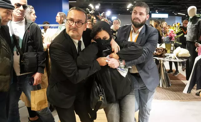 A protester is being evacuated from the BHV department store as fast fashion Shein opens its first physical store, Wednesday, Nov. 5, 2025 in Paris. (AP Photo/Thibault Camus)
