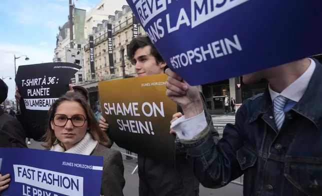 Demonstrators holds posters outside the BHV department store where fast fashion powerhouse Shein's first permanent store is set to open, Wednesday, Nov. 5, 2025 in Paris. (AP Photo/Thibault Camus)