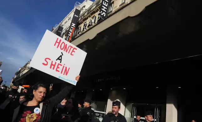 A demonstrator holds a poster reading "Shame on Shein" outside the BHV department store where fast fashion powerhouse Shein's first permanent store is set to open, Wednesday, Nov. 5, 2025 in Paris. (AP Photo/Thibault Camus)