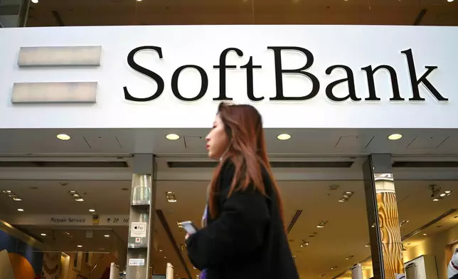 FILE - A woman walks in front of SoftBank store in Ginza shopping district in Tokyo, Jan. 20, 2020. (AP Photo/Eugene Hoshiko, File)