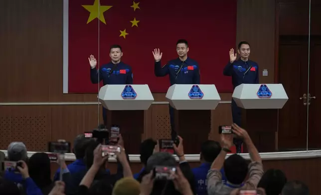 FILE - Journalists film Chinese astronauts for the upcoming Shenzhou 20 mission, from left, Wang Jie, captain Chen Dong and Chen Zhongrui wave at the Jiuquan Satellite Launch Center in northwest China, Wednesday, April 23, 2025. (AP Photo/Andy Wong, file)