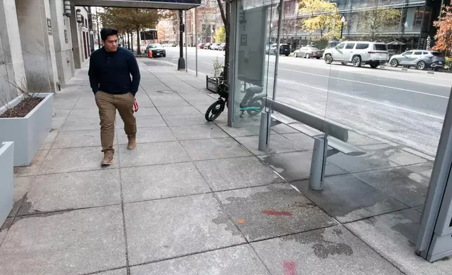 A man walks past blood stains, which have been partially washed away, one day after two National Guard soldiers were shot near the White House in Washington, Thursday, Nov. 27, 2025. (AP Photo/Cliff Owen)