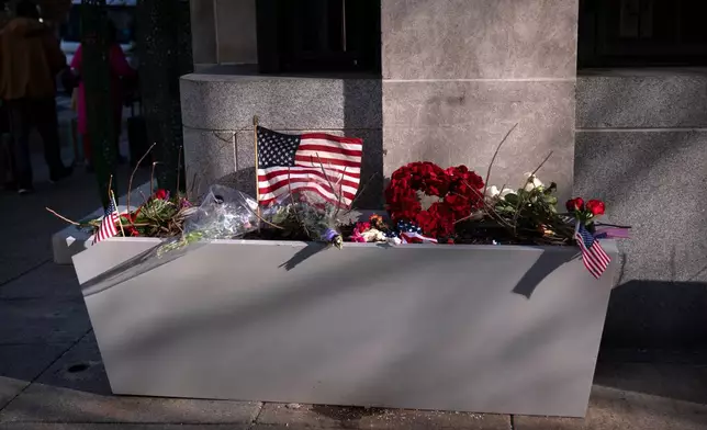 A small memorial of flags, flowers, other items are seen in a planter, Friday, Nov. 28, 2025, near the site where two National Guard members were shot in Washington. (AP Photo/Mark Schiefelbein)