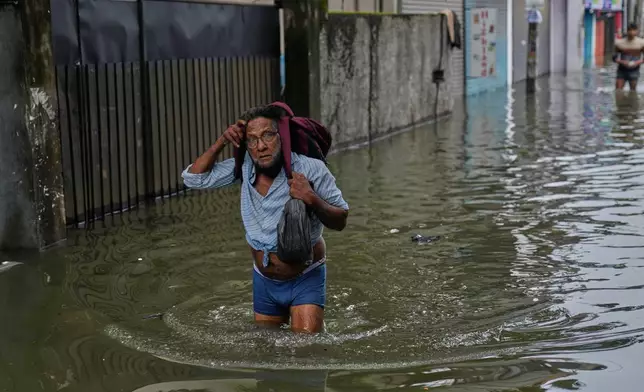 A man wades a flooded road in Colombo, Sri Lanka, Saturday, Nov, 29, 2025. (AP Photo/Eranga Jayawardena)