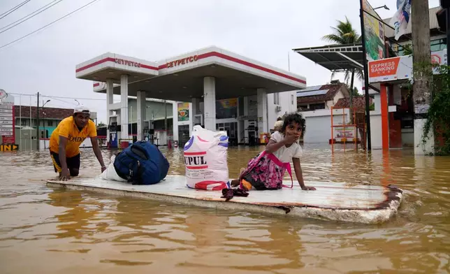 A man uses a makeshift raft to navigate a flooded street in Colombo, Sri Lanka, Saturday, Nov. 29, 2025. (AP Photo/Eranga Jayawardena)
