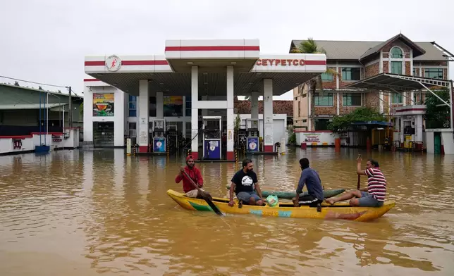 People use a boat to navigate a flooded street in Colombo, Sri Lanka, Saturday, Nov. 29, 2025. (AP Photo/Eranga Jayawardena)