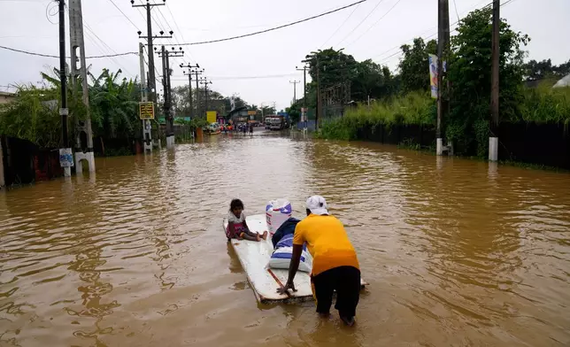 A man uses a makeshift raft to navigate a flooded street in Colombo, Sri Lanka, Saturday, Nov. 29, 2025. (AP Photo/Eranga Jayawardena)