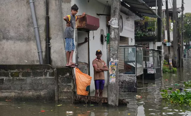 People stranded by floods wait in their submerged neighborhood in Colombo, Sri Lanka, Saturday, Nov, 29, 2025. (AP Photo/Eranga Jayawardena)
