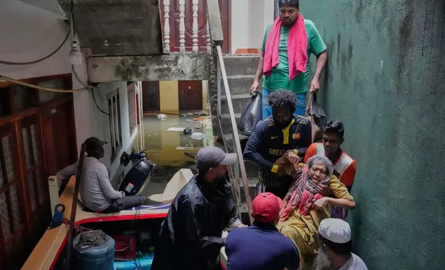 Volunteers help carry an old woman to a boat as they shift her to a safe place from a submerged neighborhood in Colombo, Sri Lanka, Saturday, Nov, 29, 2025. (AP Photo/Eranga Jayawardena)