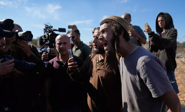 Israeli settlers take pictures of foreign activists and farmers while they attempt to disrupt the harvest of olive groves by Palestinian farmers, in the West Bank town of Silwad, Wednesday, Oct. 29, 2025. (AP Photo/Nasser Nasser)