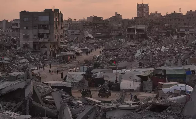 Palestinians walk through the destruction caused by the Israeli air and ground offensive in Sheikh Radwan neighborhood in Gaza City, Tuesday, Nov. 11, 2025. (AP Photo/Jehad Alshrafi)