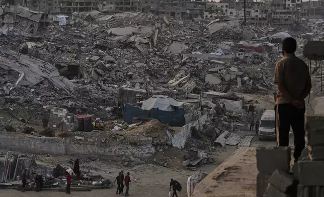 Palestinians walk through the destruction caused by the Israeli air and ground offensive in Sheikh Radwan neighborhood in Gaza City, Tuesday, Nov. 11, 2025. (AP Photo/Jehad Alshrafi)
