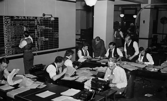FILE - Reports on the results of the nation's voting pour into Washington, D.C., Nov. 8, 1938, over Associated Press wire. There, the results from the states were consolidated into one comprehensive report by a staff of writers and tabulators shown working. Stories were constantly updated throughout the night. In background hunched over a writer is Milo Thompson, Washington chief of bureau, who directed the operation. (AP Photo, File)