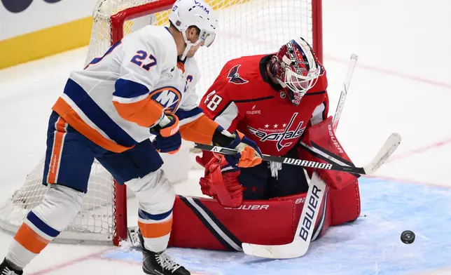 Washington Capitals goaltender Logan Thompson (48) and New York Islanders left wing Anders Lee (27) battle for the puck during the second period of an NHL hockey game, Friday, Oct. 31, 2025, in Washington. (AP Photo/Nick Wass)