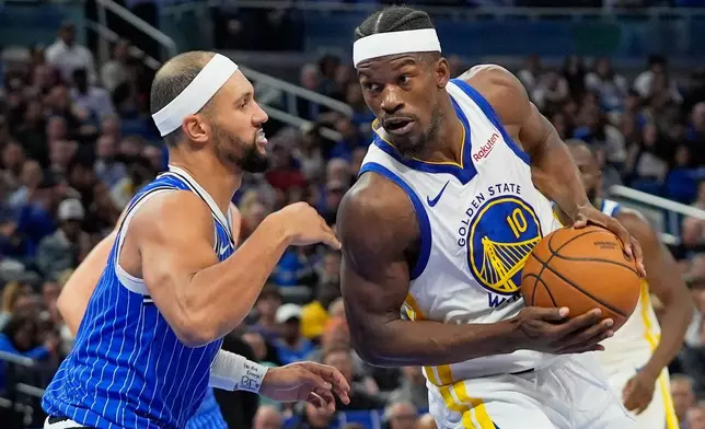 Golden State Warriors forward Jimmy Butler (10) drives around Orlando Magic guard Jalen Suggs during the second half of an NBA basketball game, Tuesday, Nov. 18, 2025, in Orlando, Fla. (AP Photo/John Raoux)