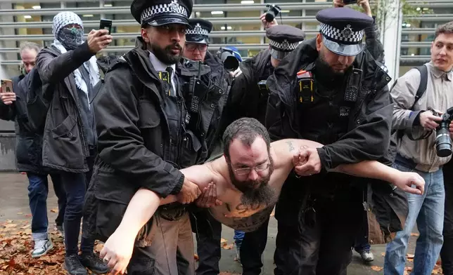 Police officers detain a protester outside the Home Office during a Palestine Action demonstration in London, Monday, Nov. 24, 2025. (AP Photo/Kirsty Wigglesworth)