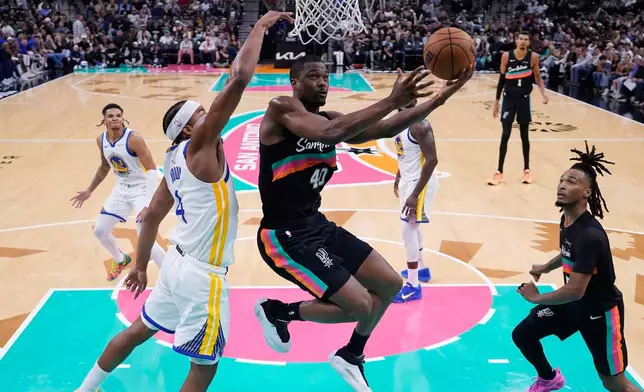 San Antonio Spurs forward Harrison Barnes (40) drives to the basket past Golden State Warriors guard Moses Moody (4) during the second half of an NBA basketball game in San Antonio, Wednesday, Nov. 12, 2025. (AP Photo/Eric Gay)