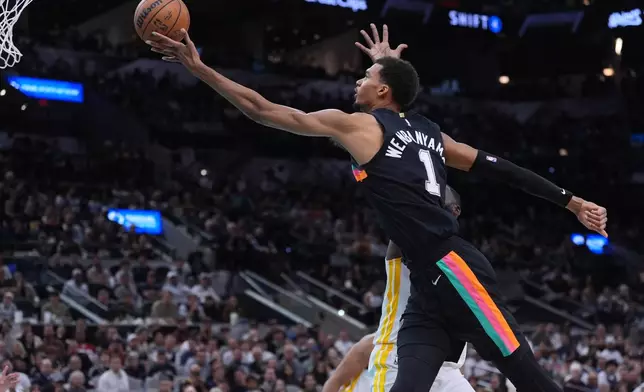 San Antonio Spurs forward Victor Wembanyama (1) drives to the basket past Golden State Warriors forward Draymond Green during the second half of an NBA basketball game in San Antonio, Wednesday, Nov. 12, 2025. (AP Photo/Eric Gay)