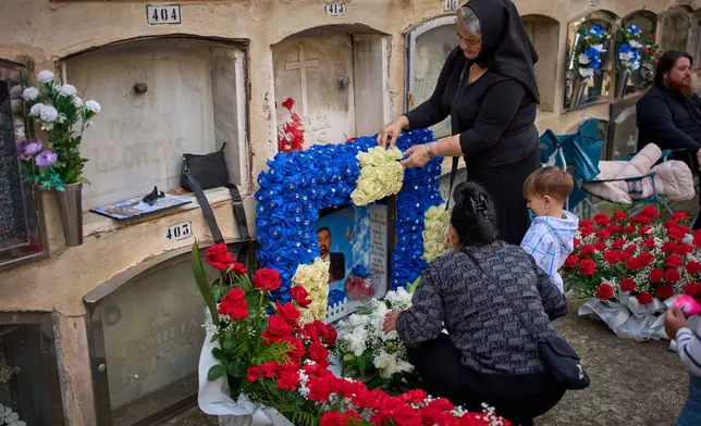 People place flowers on a grave during All Saints' Day, a Catholic holiday to honor saints and remember deceased relatives, at a municipal cemetery in Barcelona, Spain, Saturday, Nov. 1, 2025. (AP Photo/Emilio Morenatti)