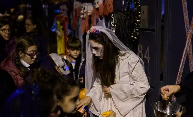 People dressed in scary costumes take part in a Halloween celebration that gives sweets to children in Paracuellos del Jarama, Spain, Friday, Oct. 31, 2025. (AP Photo/Manu Fernandez)