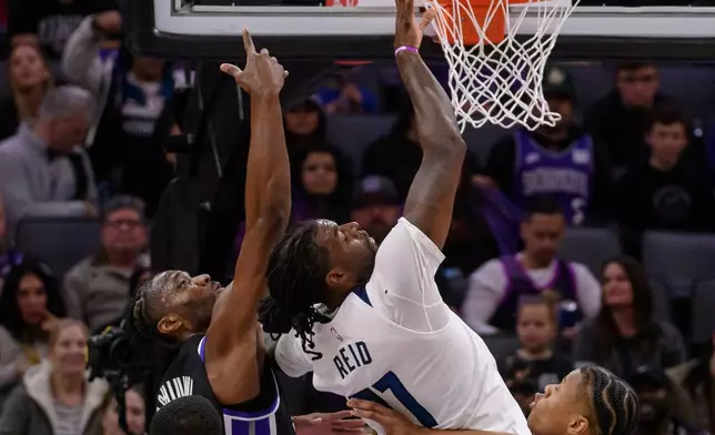 Sacramento Kings forward Precious Achiuwa, left, shoots over Minnesota Timberwolves center Naz Reid during the first half of an NBA basketball game in Sacramento, Calif., Monday, Nov. 24, 2025. (AP Photo/Randall Benton)