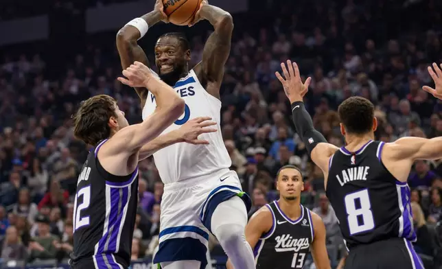 Minnesota Timberwolves forward Julius Randle passes the ball over Sacramento Kings center Maxime Raynaud during the first half of an NBA basketball game in Sacramento, Calif., Monday, Nov. 24, 2025. (AP Photo/Randall Benton)