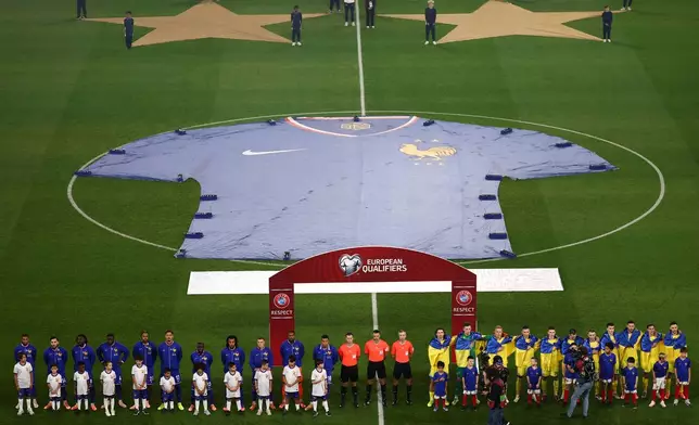 Ukraine's and France's team players stand on the pitch for the national anthems and for a minute of silence in tribute of the victims of the Nov.13, 2015 Paris attacks, ahead of the 2026 World Cup qualifiers Europe zone group D football match between France and Ukraine at the Parc des Princes stadium, Thursday, Nov. 13, 2025 in Paris. ( Franck Fife, Pool photo via AP)