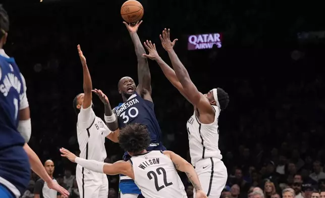 Minnesota Timberwolves' Julius Randle, center, shoots over Brooklyn Nets' Ziaire Williams, left, Day'Ron Sharpe, right, and Jalen Wilson, below during the second half of an NBA basketball game Monday, Nov. 3, 2025, at Barclays Center in New York. (AP Photo/Frank Franklin II)