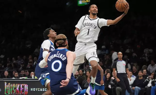 Brooklyn Nets' Ziaire Williams (1) drives past Minnesota Timberwolves' Donte DiVincenzo (0) and Jaden McDaniels (3) during the first half of an NBA basketball game Monday, Nov. 3, 2025, at Barclays Center in New York. (AP Photo/Frank Franklin II)