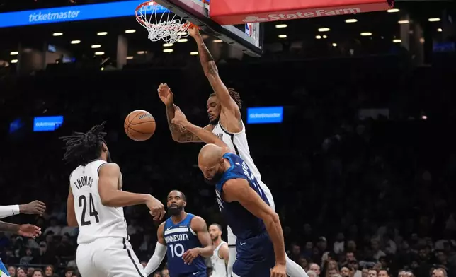 Brooklyn Nets' Nic Claxton, right, dunks the ball in front of Minnesota Timberwolves' Rudy Gobert during the first half of an NBA basketball game Monday, Nov. 3, 2025, at Barclays Center in New York. (AP Photo/Frank Franklin II)