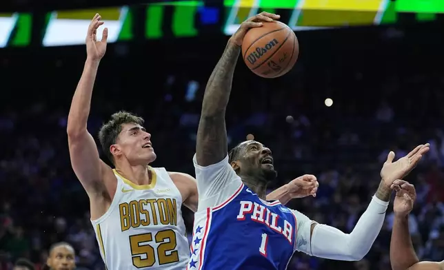 Philadelphia 76ers' Andre Drummond (1) wins the rebound over Boston Celtics' Luka Garza during the first half of an NBA basketball game Tuesday, Nov. 11, 2025, in Philadelphia. (AP Photo/Matt Rourke)