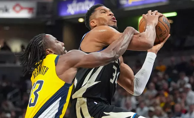 Indiana Pacers guard/forward Aaron Nesmith (23) fouls Milwaukee Bucks forward Giannis Antetokounmpo (34) during the first half of an NBA basketball game in Indianapolis, Monday, Nov. 3, 2025. (AP Photo/Michael Conroy)