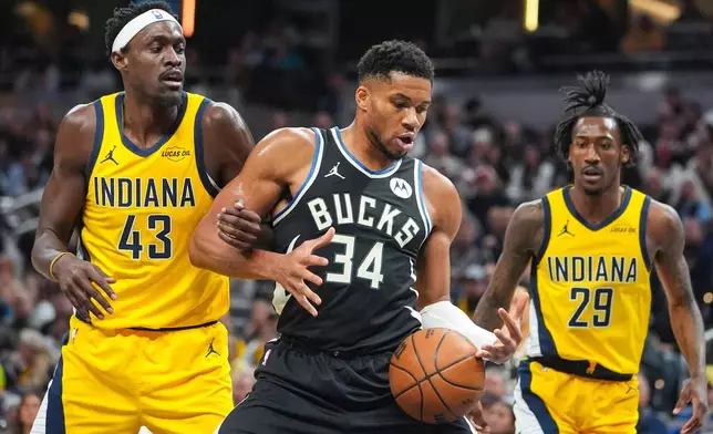 Milwaukee Bucks forward Giannis Antetokounmpo (34) gets tied up with Indiana Pacers forward Pascal Siakam (43) during the first half of an NBA basketball game in Indianapolis, Monday, Nov. 3, 2025. (AP Photo/Michael Conroy)