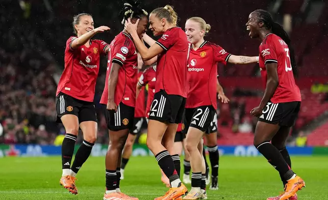 Manchester United's Melvine Malard, center left, celebrates with team-mates after scoring their side's first goal during the women's Champions League opening phase soccer match between Manchester United and Paris Saint-Germain in Manchester, Wednesday, Nov. 12, 2025. (Martin Rickett/PA via AP)
