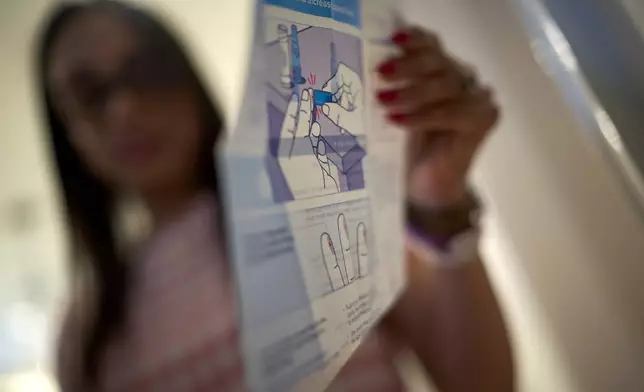Ruth Wilson, who has lupus, unpacks a kit to prick her finger for a blood sample to share with her doctor whenever she experiences a flare up, Jan. 12, 2025, at her home in Littleton, Mass. (AP Photo/David Goldman)