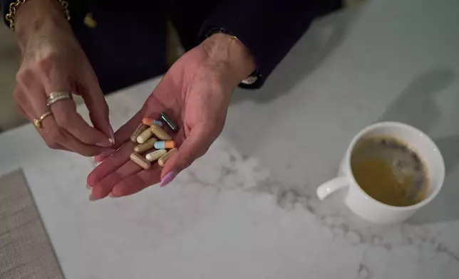 Ruth Wilson, whose has lupus, takes her prescription medications and supplements before going to work on Jan. 13, 2025, in Littleton, Mass. (AP Photo/David Goldman)