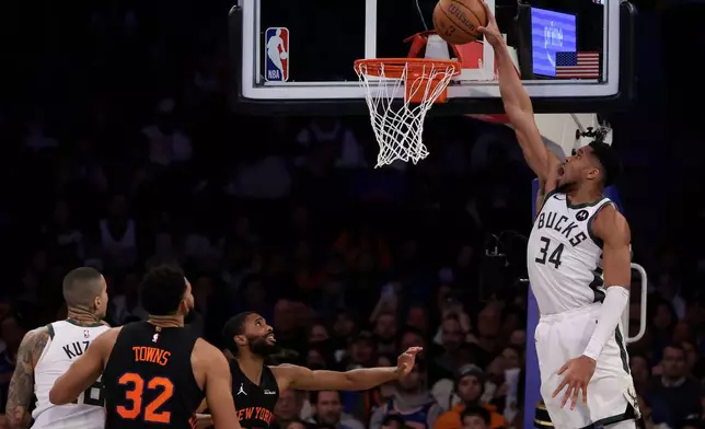 Milwaukee Bucks forward Giannis Antetokounmpo (34) dunks the ball over New York Knicks guard Mikal Bridges during the second half of an NBA Cup basketball game, Friday, Nov. 28, 2025, in New York. (AP Photo/Adam Hunger)