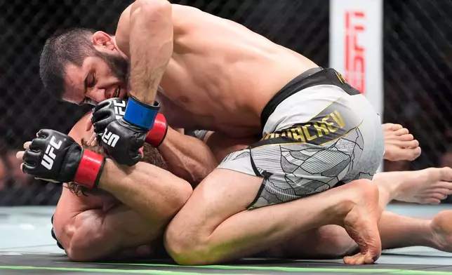 Russia's Islam Makhachev, top, grapples with Australia's Jack Della Maddalena, bottom, during the third round of a welterweight title bout at the UFC 322 mixed martial arts event, Saturday, Nov. 15, 2025, in New York. (AP Photo/Yuki Iwamura)