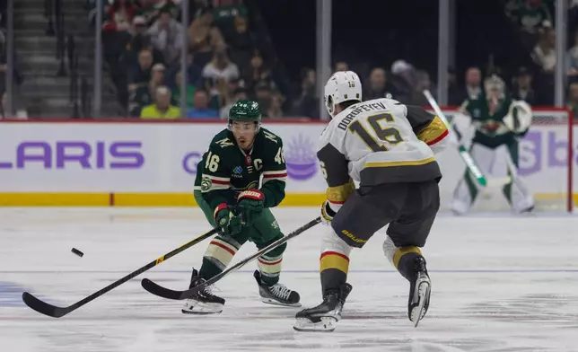 Minnesota Wild player Jared Spurgeon, left, and Vegas Golden Knights player Pavel Dorofeyev go for the puck during the first period of an NHL hockey game, Sunday, Nov. 16, 2025, in St. Paul, Minn. (AP Photo/Lily Dozier)