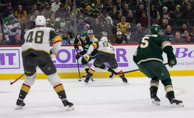 Minnesota Wild player Kirill Kaprizov, left, controls the puck against Vegas Golden Knights player Mitch Marner during the second period of an NHL hockey game, Sunday, Nov. 16, 2025, in St. Paul, Minn. (AP Photo/Lily Dozier)