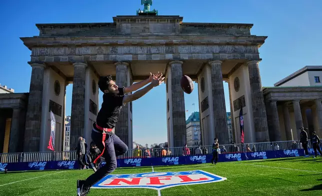 Children play flag football on a mini flag football field, set up in front of the Brandenburg Gate in Berlin, Germany, Thursday, Nov. 6, 2025, during an event promoting the NFL ahead of the upcoming game between the Indianapolis Colts and the Atlanta Falcons. (AP Photo/Ebrahim Noroozi)