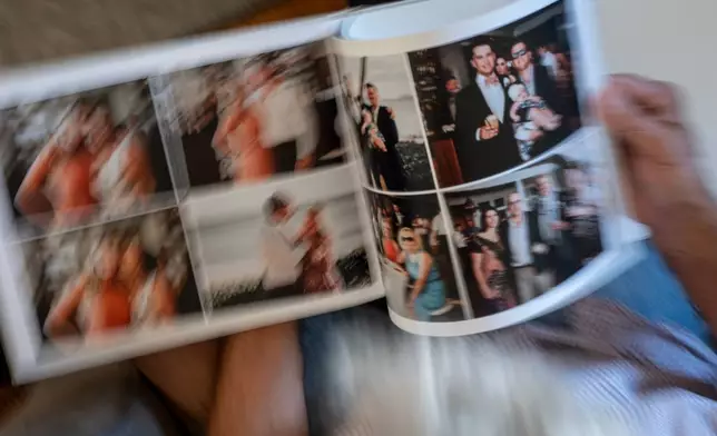 Christy Morrill, 72, who lost decades of memories to autoimmune encephalitis, looks over a photo album of his son's wedding, at his home, Tuesday, Aug. 19, 2025, in San Carlos, Calif. (AP Photo/David Goldman)