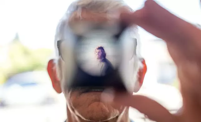 Christy Morrill, 72, who lost decades of memories to autoimmune encephalitis, holds up a viewfinder with a slide film of himself as a college student, Wednesday, Aug. 20, 2025, at his home in San Carlos, Calif. (AP Photo/David Goldman)
