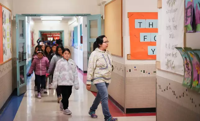 Renee Avugiak, originally from Chefornak, Alaska, near the villages of Kipnuk and Kwigillingok that were heavily damaged by ex-Typhoon Halong, leads her class through the hallways at College Gate Elementary, where students spend half their time learning in Yup'ik language immersion, Thursday, Oct. 30, 2025, in Anchorage, Alaska. (AP Photo/Lindsey Wasson)