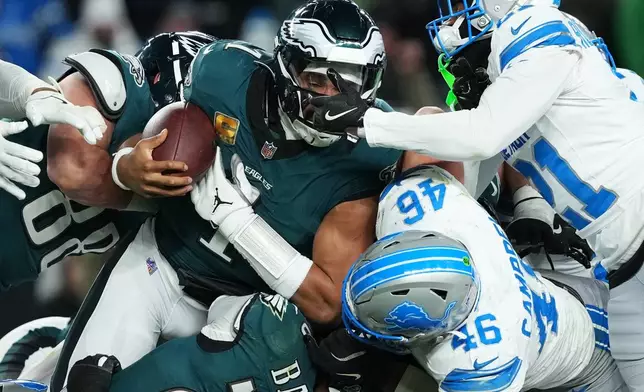 Philadelphia Eagles quarterback Jalen Hurts (1) is stopped with the ball during the second half of an NFL football game by Detroit Lions linebacker Jack Campbell (46) and Lions cornerback Amik Robertson (21) Sunday, Nov. 16, 2025, in Philadelphia. (AP Photo/Matt Slocum)