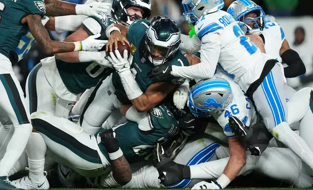 Philadelphia Eagles quarterback Jalen Hurts (1) is stopped with the ball during the second half of an NFL football game by Detroit Lions linebacker Jack Campbell (46) and Lions cornerback Amik Robertson (21) Sunday, Nov. 16, 2025, in Philadelphia. (AP Photo/Matt Slocum)