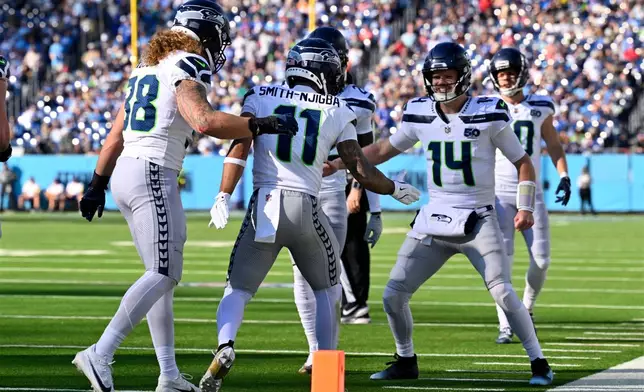Seattle Seahawks wide receiver Jaxon Smith-Njigba (11) celebrates his touchdown pass reception with quarterback Sam Darnold (14) during the second half of an NFL football game against the Tennessee Titans Sunday, Nov. 23, 2025, in Nashville, Tenn. (AP Photo/John Amis)