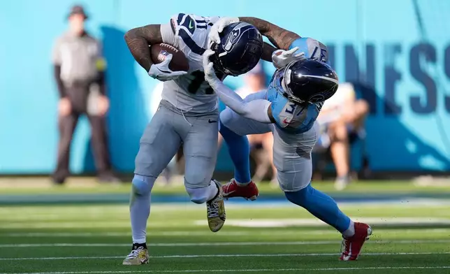 Tennessee Titans safety Amani Hooker (37) tackles Seattle Seahawks wide receiver Jaxon Smith-Njigba (11) during the second half of an NFL football game Sunday, Nov. 23, 2025, in Nashville, Tenn. (AP Photo/George Walker IV)